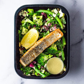 A rectangular container with a slice of grilled salmon with green beans, broccoli, kale, and pea salad with lemon vinaigrette.