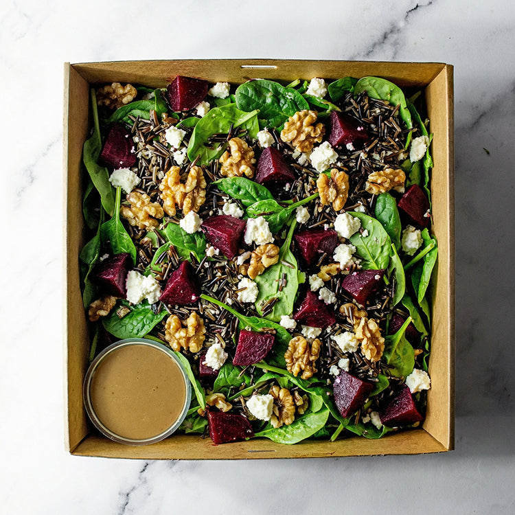 Box of beetroot, walnuts, feta, mixed rice, baby spinach, and balsamic vinaigrette on a marble surface