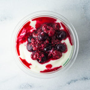 A top view of a breakfast tub with coconut yoghurt and berry compote.
