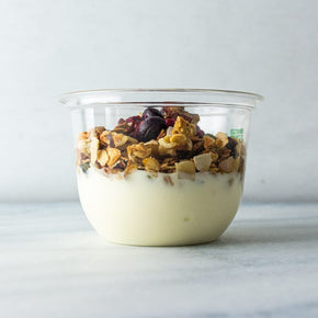 A clear plastic tub filled with granola, yogurt, and berry compote.