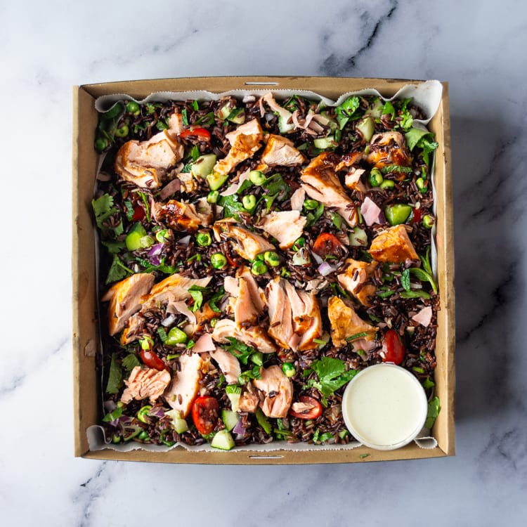 Box of salad with miso salmon, mixed rice, cherry tomatoes, cucumber, red onion, pickled ginger, wasabi peas and wasabi mayo