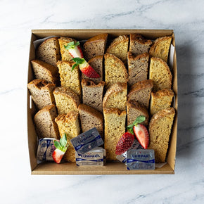 Box of sweet loaf slices in mango and banana flavours on a marble surface.