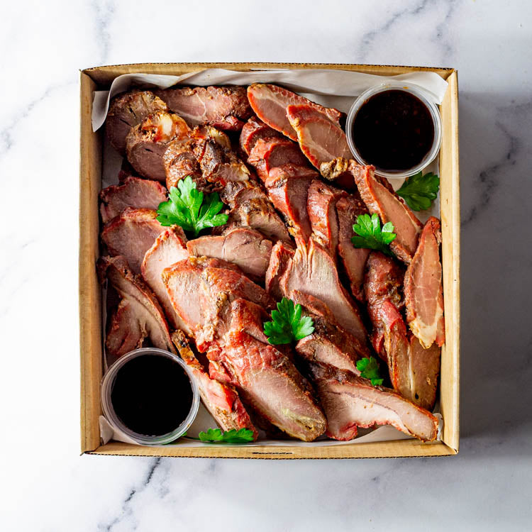 Box of char Siu pork slices with sweet soy on a marble surface