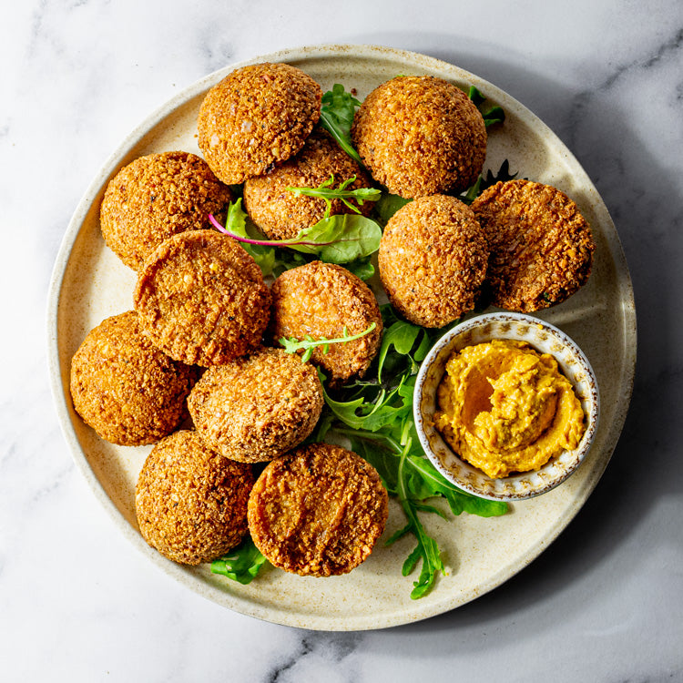 Plate of falafel balls with a side of pumpkin hummus on a marble surface