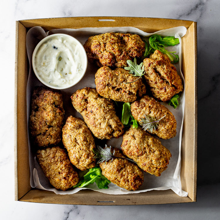 Box of spiced lamb kofta paired with creamy tzatziki on a marble surface