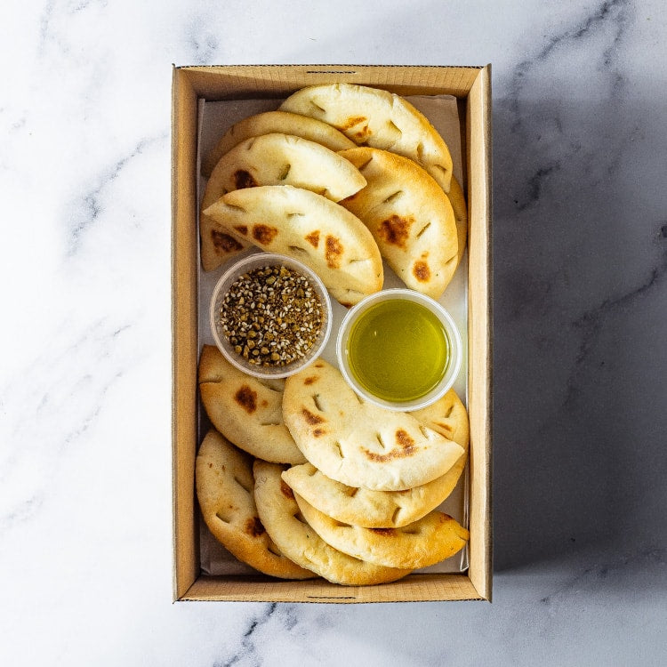 Box of flatbreads with olive oil and za'atar on a marble surface