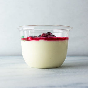 A clear plastic tub filled with yoghurt topped with berry compote.